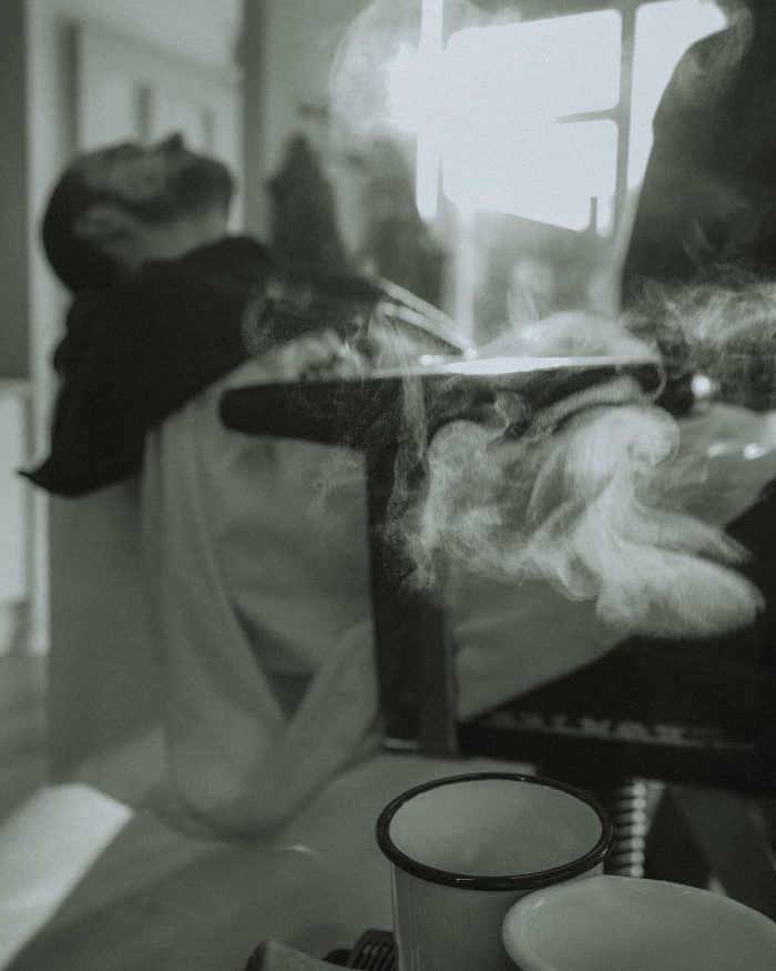 Black and white image of man getting beard cut