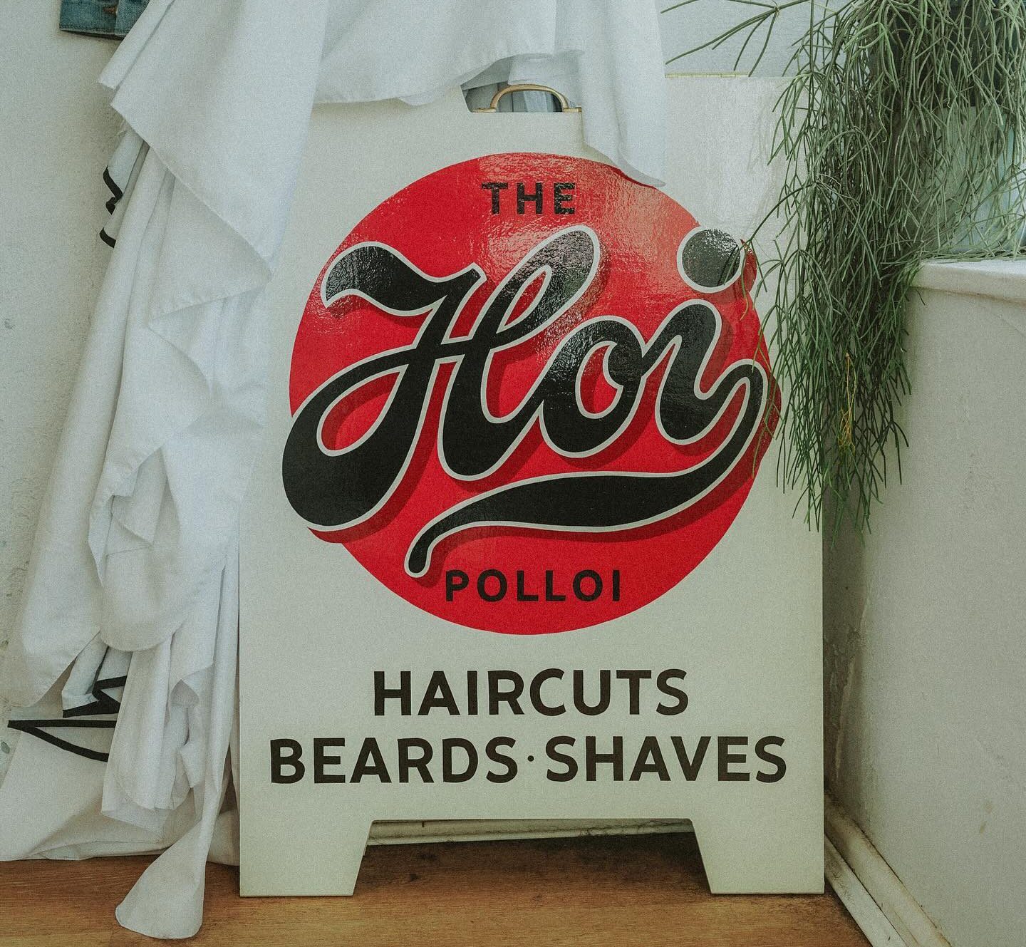 Signboard poster that says The Hoi Polloi, haircuts, beards, shaves.
